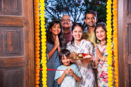 Photo for Indian family entering new home called gruhapravesh with puja thali and keys - Royalty Free Image