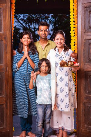 Photo for Indian young family entering new home called gruha pravesh with puja thali and keys - Royalty Free Image