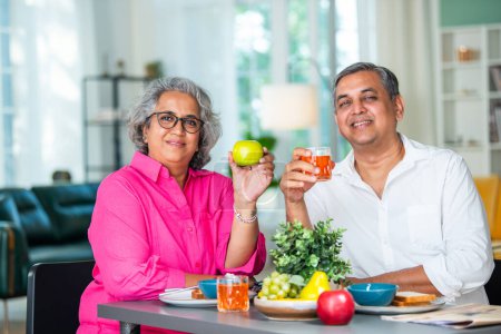 Foto de A happy mature Indian asian senior couple having breakfast together at home. - Imagen libre de derechos