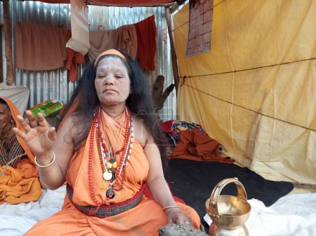 Téléchargez les photos : Calcutta, West Bengal,India 8th January 2023:Sadhavi or women sadhu smeared with vibhuty or holy ash waiting for devotees to bless at Gangasagar transit camp or akhara . - en image libre de droit