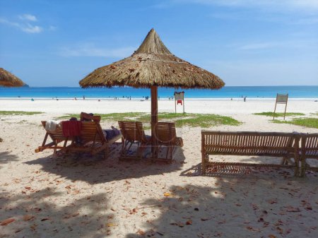 Téléchargez les photos : Radhanagar, Havelock, Andaman 2 Avril 2023 : Parapluie de foin, Chaises de tourisme à Radhanagar plage de mer avec un fond d'eau bleue de l'Océan Indien. Cette plage est considérée comme la meilleure plage d'Asie - en image libre de droit