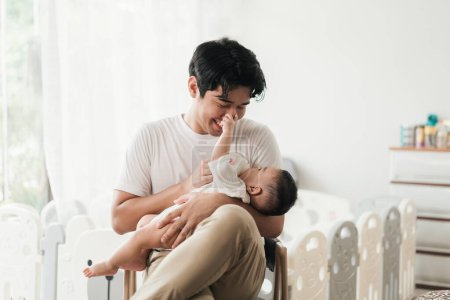 Téléchargez les photos : Heureux jeune père asiatique nourrissant bébé garçon mignon avec du lait de biberon. Petit bébé buvant du lait et touchant sur le visage père. Concept de fête des pères. - en image libre de droit