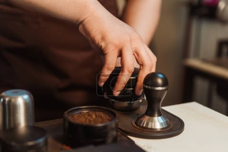 Photo for Closeup hand of barista preparation tampering coffee in portafilter for making espresso. Coffee making concept. - Royalty Free Image