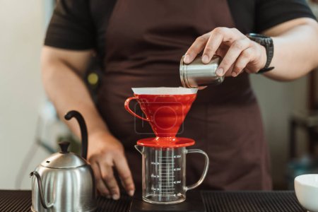 Téléchargez les photos : Concept de café de barre lente, main étroite de barista versant le café moulu dans le goutteur v60 pour faire le filtre de café. - en image libre de droit