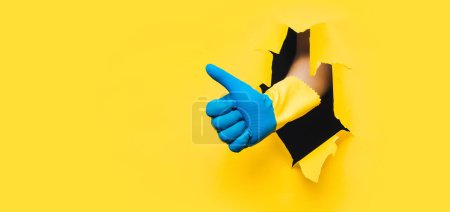 Téléchargez les photos : Main en caoutchouc bleu-jaune gant montre pouce. Comme ça. Concept pour mettre fin à la quarantaine du coronavirus, résolution de problèmes réussie. Couleurs du drapeau de l'Ukraine. Jardinier, plombier. Espace de copie. - en image libre de droit