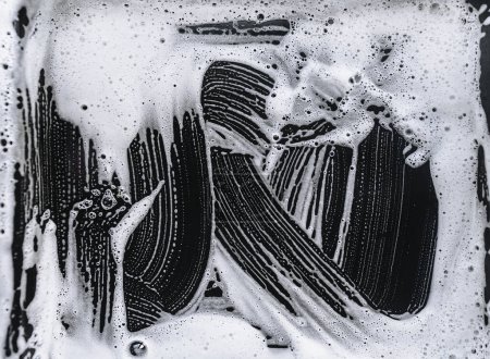 Foto de Espuma y jabón sobre fondo negro. Patrón abstracto. El concepto de lavado de la cacerola aceitosa o coche negro. - Imagen libre de derechos