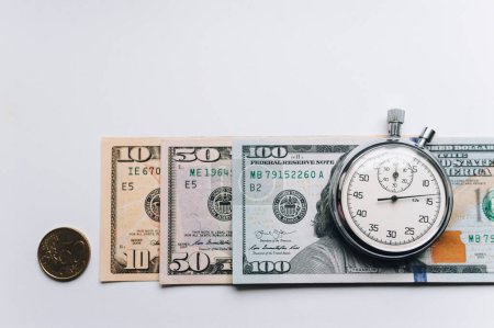Photo for Stopwatch and dollars. Time is money concept. Banknotes and coins. White background, copy space. - Royalty Free Image