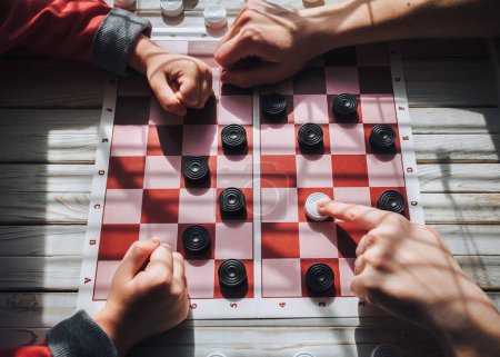 Photo for Parents teach their children to play checkers. The child is taught to play checkers. Play board games. Checkerboard. - Royalty Free Image