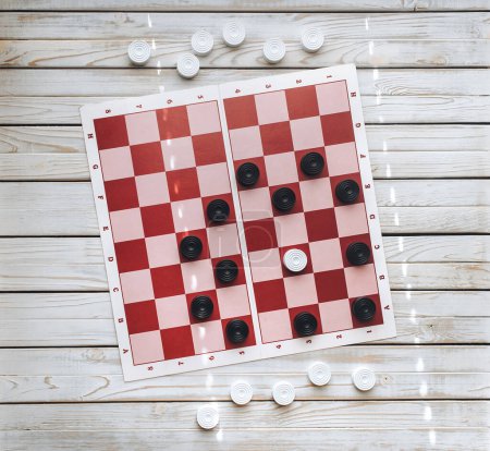 Foto de Damas blancas y negras en un tablero de ajedrez de papel con celdas rosas y rojas. Vista desde arriba. Logik concepto de juego. - Imagen libre de derechos