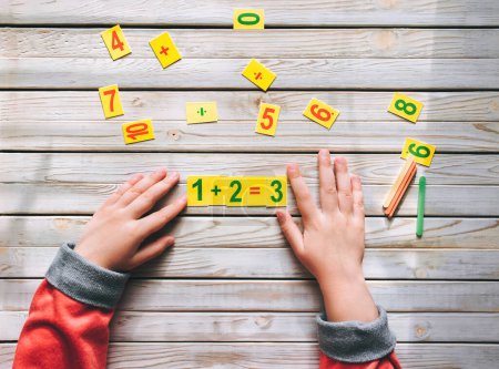 Photo for First-grader learn to count. The child decides a mathematical example. Basic knowledge. - Royalty Free Image