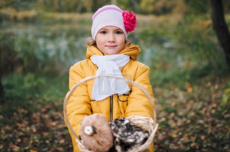 Téléchargez les photos : La fille tient un panier avec des champignons Lactarius. Les parents apprennent à leur petite fille à cueillir des champignons. Enfants cueilleurs de champignons. - en image libre de droit