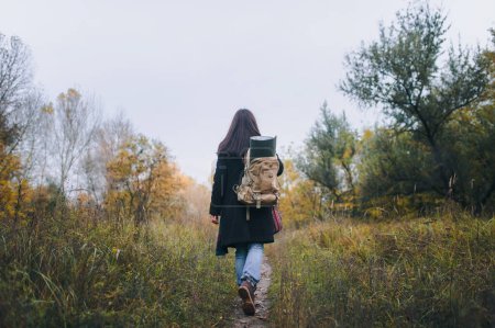 Téléchargez les photos : Jeune fille touriste, marchant dans une forêt avec un gros sac à dos sur le dos
. - en image libre de droit
