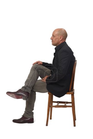 Foto de Vista lateral de un hombre sentado en una silla con patas cruzadas sobre fondo blanco - Imagen libre de derechos
