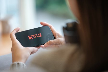 Photo for CHIANG MAI, THAILAND - Jun 23, 2023 : A woman hold apple iPhone 14 pro with Netflix entertainment platform in living room at home. High quality photo - Royalty Free Image