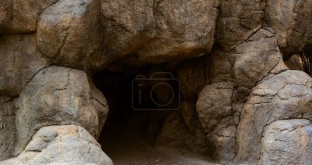Téléchargez les photos : Entrée de la grotte et grosses roches brunes - en image libre de droit