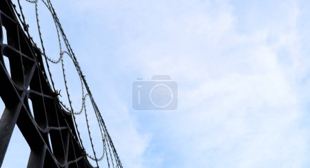 Runder Stacheldraht auf Eisenzaun und Himmelsblick von unten nach oben. Sperrgebiet, illegale Einwanderung und Gefängniskonzept Hintergrundbild