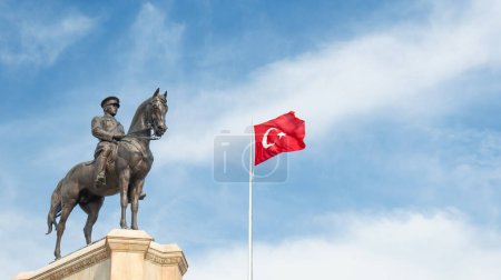 Turkish flag waving in the sky and Ataturk statue. Mustafa Kemal Ataturk monument and Turkish flag on beautiful blue sky background.