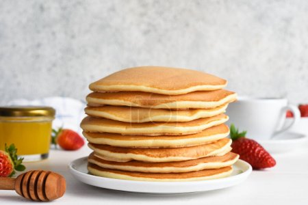 Téléchargez les photos : Empilement de crêpes au miel, crêpes maison aux fraises pour le petit déjeuner - en image libre de droit