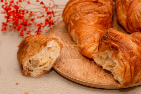 Photo for Closeup shot of croissants liying on a wooden textured plate on a jute textured napkin. French traditions. - Royalty Free Image