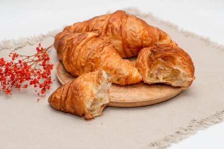 Photo for Shot of croissants liying on a wooden textured plate on a jute textured napkin. French traditions. - Royalty Free Image