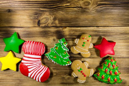 Photo for Tasty festive Christmas gingerbread cookies in the shape of Christmas tree, Gingerbread man, star and Christmas sock on wooden table. Top view - Royalty Free Image