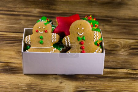 Photo for Tasty festive Christmas gingerbread cookies in the shape of Christmas tree, stars,  Gingerbread man and woman in box on wooden table - Royalty Free Image