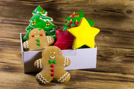Photo for Tasty festive Christmas gingerbread cookies in the shape of Christmas tree, stars,  Gingerbread man and woman in box on wooden table - Royalty Free Image