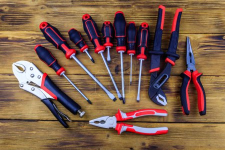 Téléchargez les photos : Set of different pliers and screwdrivers on wooden background. Top view - en image libre de droit
