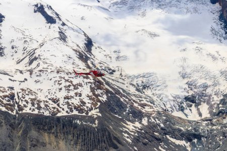 Hubschrauber fliegt über die verschneiten Schweizer Alpen in der Schweiz