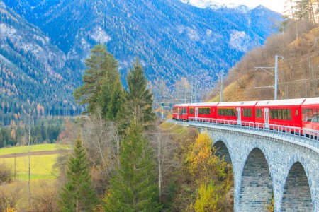 Téléchargez les photos : Train de voyageurs rouge sur le chemin de fer rhétien dans le canton de Graubunden, en Suisse à l'automne - en image libre de droit