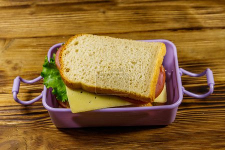 Boîte à lunch avec sandwichs sur une table en bois