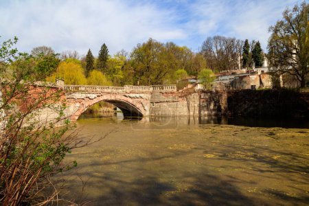 Alte gebogene Ziegelbrücke über einen Teich im Sharovka Palace Park im Gebiet Charkow, Ukraine