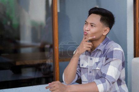 Foto de Un hombre que parece confundido mientras está sentado en un café. - Imagen libre de derechos