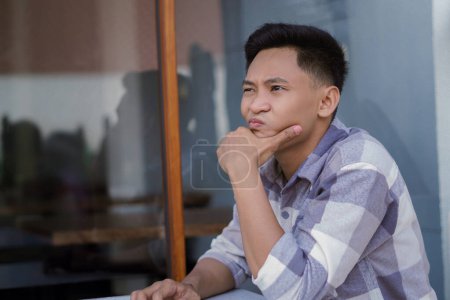 Foto de Un hombre que parece confundido mientras está sentado en un café. - Imagen libre de derechos