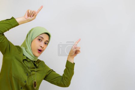 Téléchargez les photos : Belle jeune femme asiatique pointant son doigt vers le haut. Concept publicitaire pour le modèle hijab - en image libre de droit