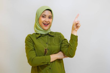 Foto de Hermosa joven asiática señalando con el dedo hacia arriba. Concepto publicitario para el modelo hijab - Imagen libre de derechos