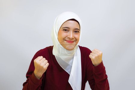 Cheerful Asian muslim woman showing high spirit during independence day celebration, isolated by white background. Indonesia's independence day concept.     
