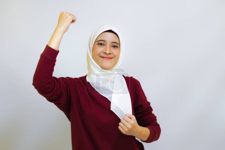 Mujer musulmana asiática alegre mostrando gran espíritu durante la celebración del día de la independencia, aislada por el fondo blanco. Concepto del día de la independencia de Indonesia.     