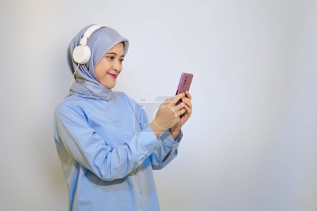 feliz joven mujer musulmana asiática escuchando música con auriculares. concepto de publicidad mujer musulmana. escuchar música concepto