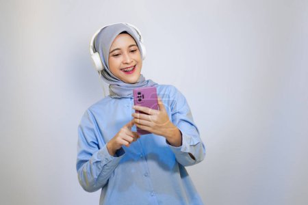 Foto de Feliz joven mujer musulmana asiática escuchando música con auriculares. concepto de publicidad mujer musulmana. escuchar música concepto - Imagen libre de derechos