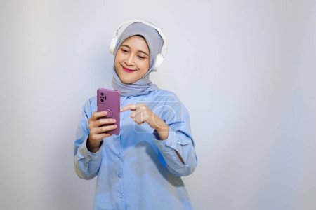 Happy young Asian muslim woman listening music with headphone. muslim woman advertising concept. listening music concept     