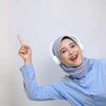 Young Asian woman pointing up while enjoying music on headphone. listen music concept 