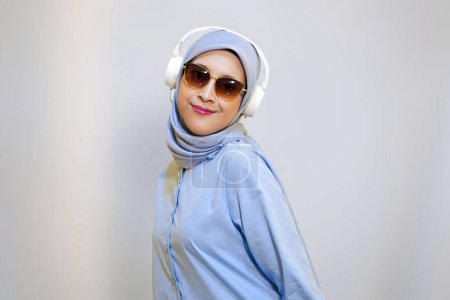 Muslim woman wearing headphone and sunglasses enjoying the music