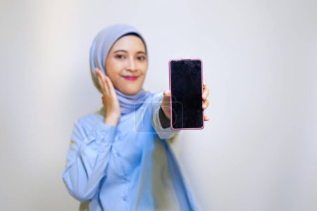 Muslim woman showing her phone display. Focus on mobile phone for advertising.