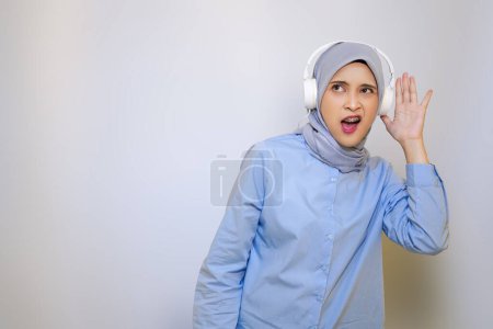 Foto de Alegre musulmán asiático mujer en azul camisa escuchar música en auriculares - Imagen libre de derechos
