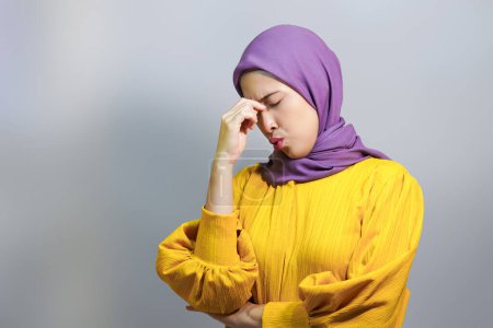 Exhausted young muslim woman in hijab tired after working, having headache. 