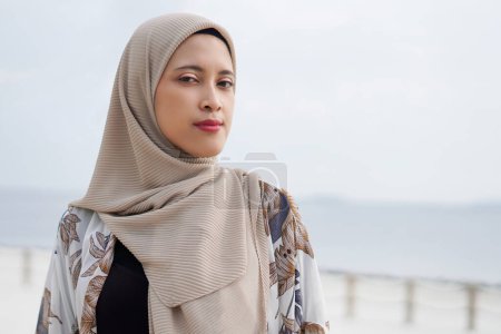 Jolie femme musulmane profitant du soleil sur la plage portant un cardigan.