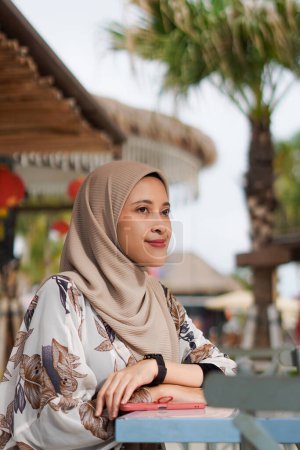 Contemplación junto al mar. Mujer musulmana feliz disfrutando del ambiente de playa