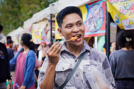 Indonesischer Mann isst Koriander oder Telor Gulung, Indonesisches Streetfood-Konzept.