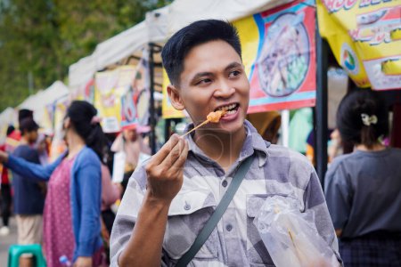 Indonesischer Mann isst Koriander oder Telor Gulung, Indonesisches Streetfood-Konzept.